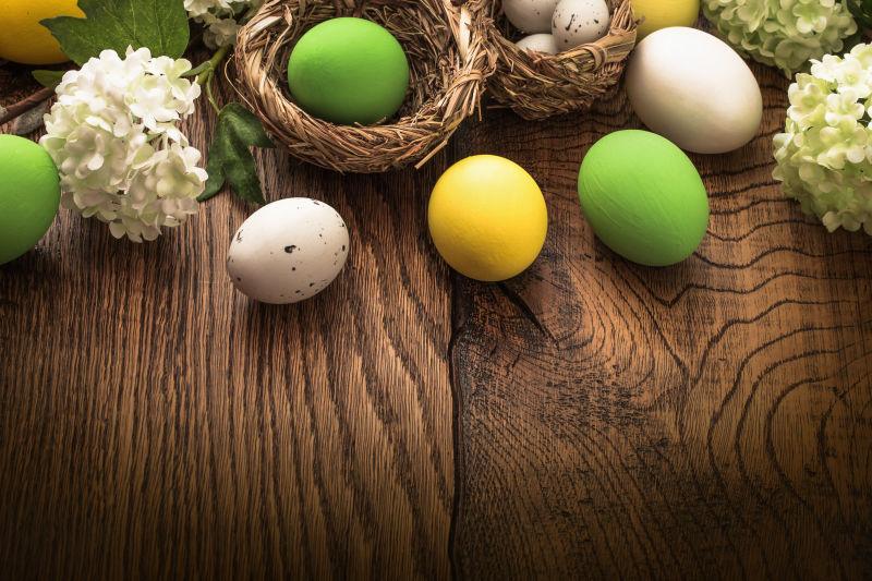 木纹理桌上的复活节彩蛋和白色花朵
