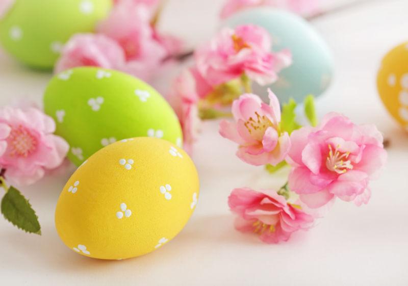 白色桌上的复活节彩蛋和粉色花朵