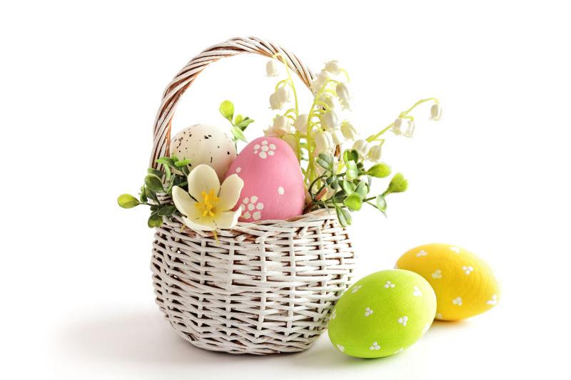 白色背景上的小花篮里的复活节彩蛋和白色花朵
