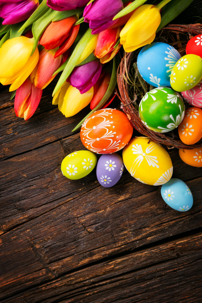 木桌上的复活节彩蛋与颜色鲜艳的郁金香