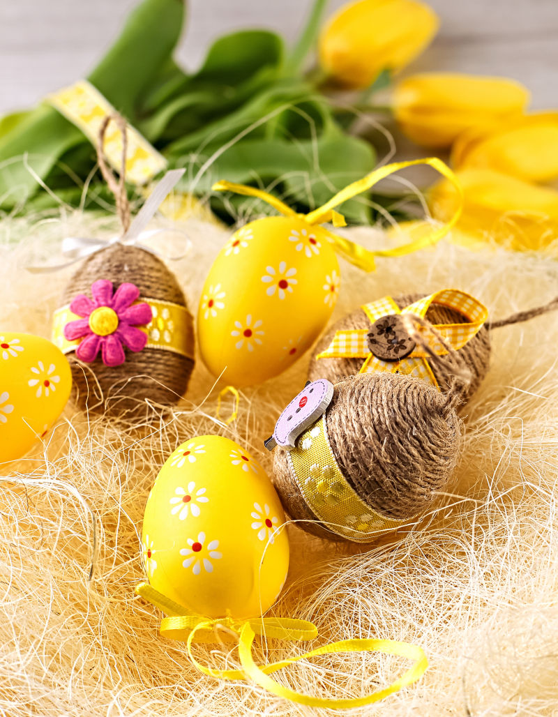 黄色丝线背景上的复活节彩蛋和黄色郁金香