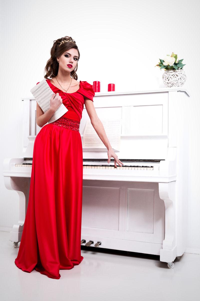 白色背景中拿着音符站在钢琴旁穿红色连衣裙的美女