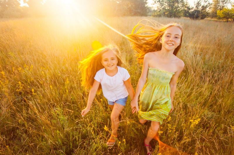 两个美丽的姐妹在自然公园的草坪上奔跑