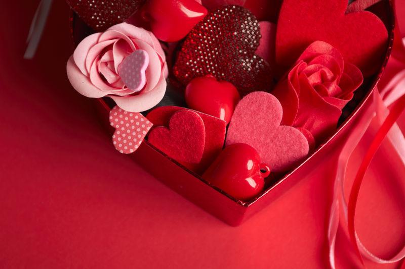 红色桌面上的一堆玫瑰花和爱心饰品