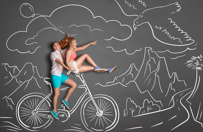 粉笔画背景中的一对浪漫的情侣在山地骑车