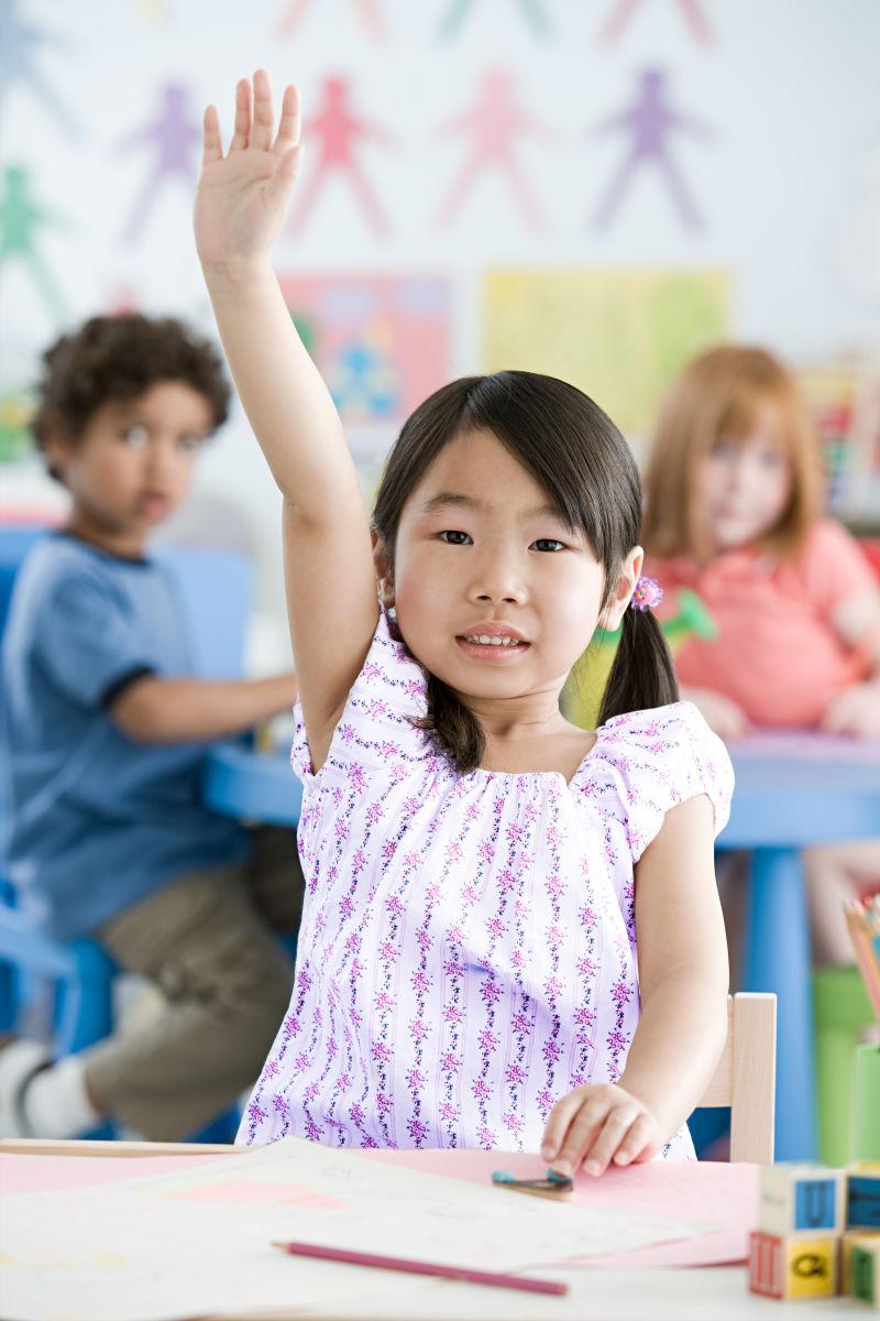 在教室内高举手的小女孩