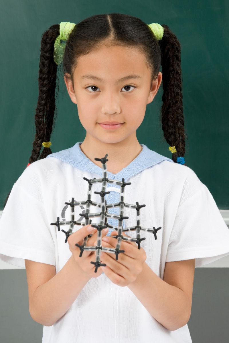 站在教室的黑板前拿着科学模型的女孩
