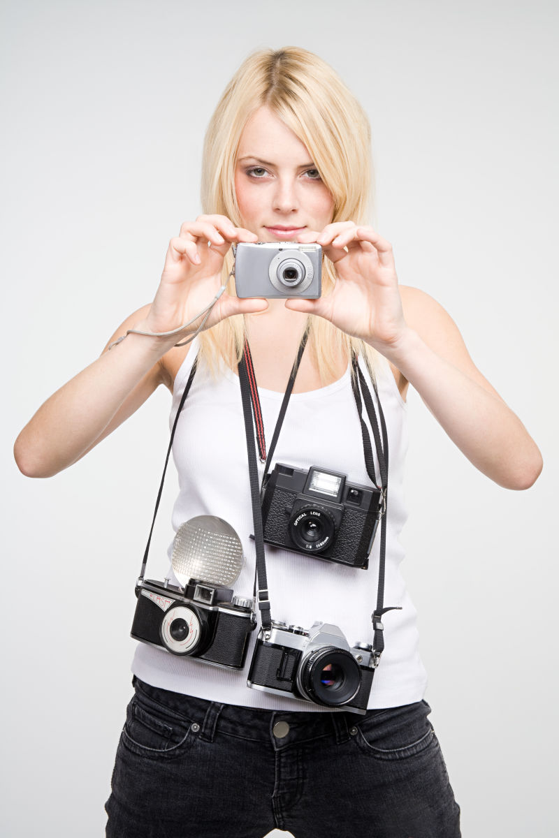 喜欢拍照的年轻人拿着一堆照相机