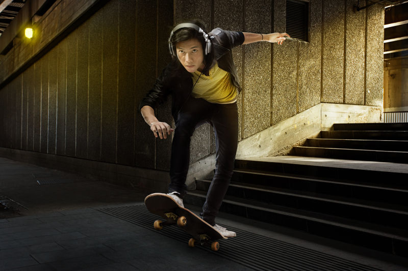 年轻男人在地铁站带耳麦玩滑板