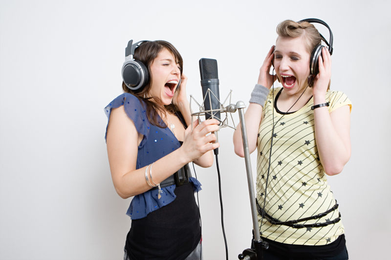 戴着耳机在话筒前唱歌的两个女人