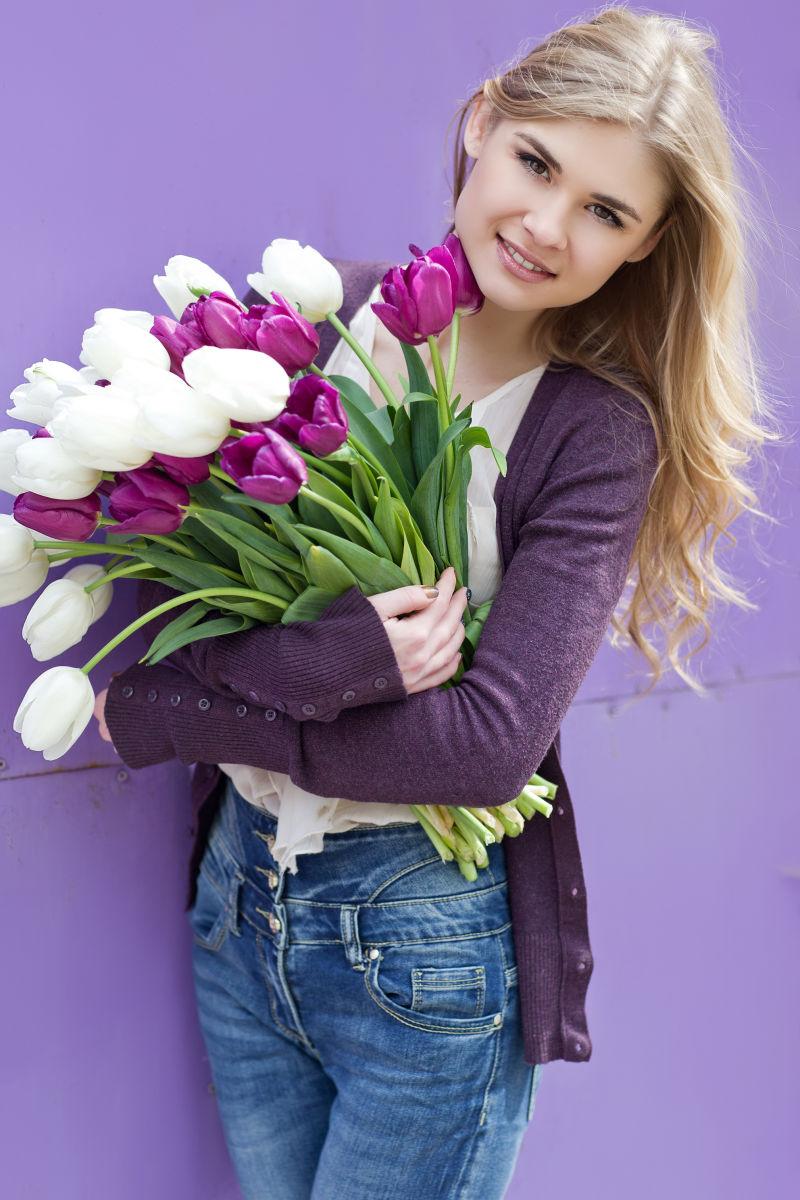 紫色背景中女孩抱着郁金香花束