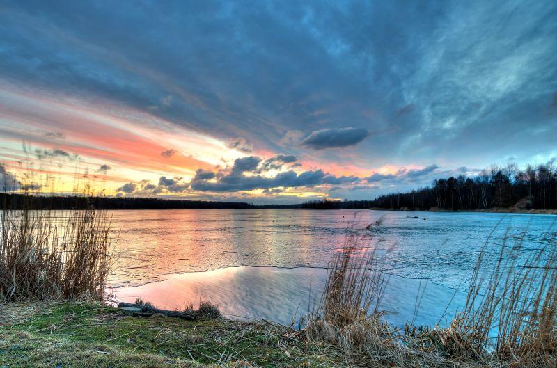 日落时有云的天空下的结冰的湖面