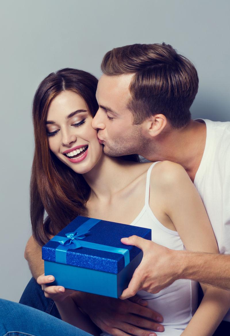 男人拿着蓝色的礼盒亲吻着女人