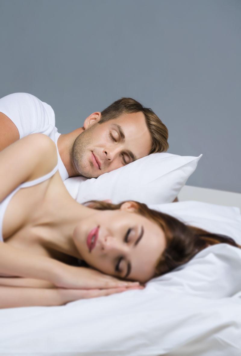 躺在床上睡觉的年轻夫妇