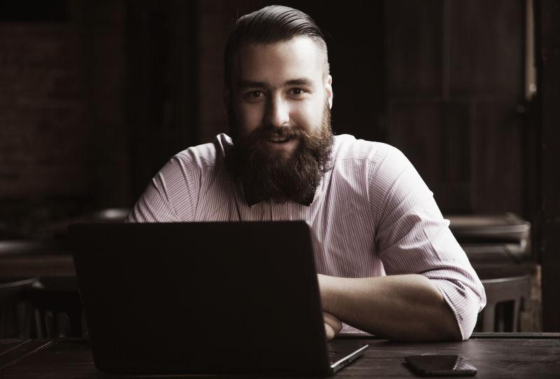 年轻的有胡子男人用笔记本电脑