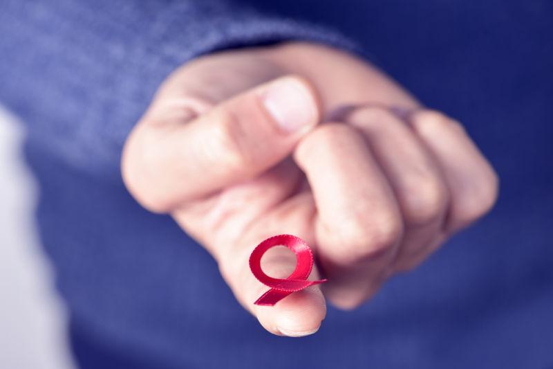 一个年轻人的手上带着一条红色的丝带来对抗艾滋病
