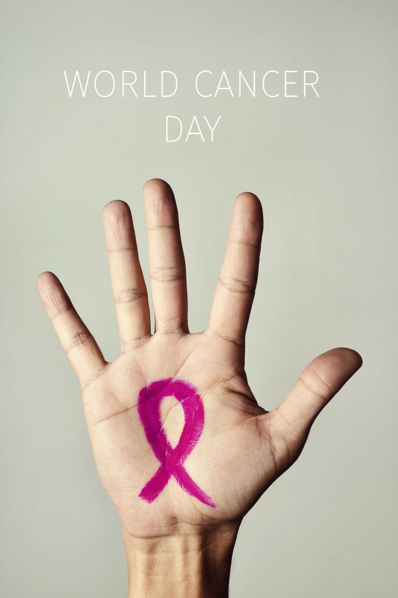 一个粉红色的缎带在一个年轻的白种人的手掌和世界癌症日