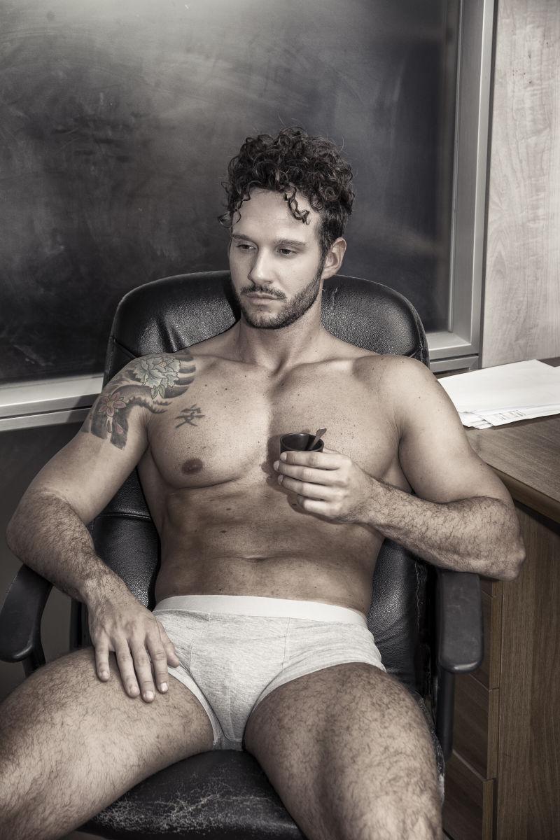 性感的年轻男子穿着内衣坐在桌上喝咖啡身体肌肉发达