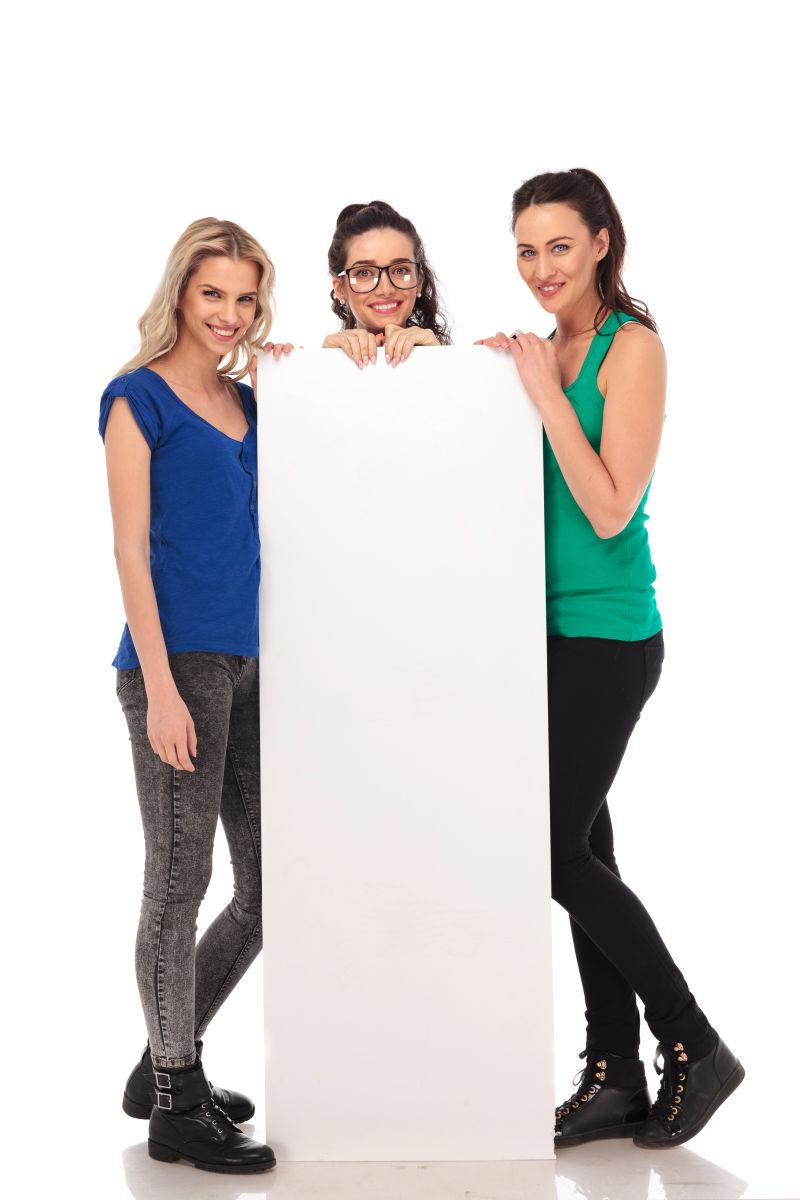 白色背景上三个拿着一个空白广告牌的美女