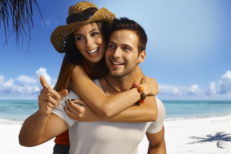 快乐的恋人在夏日的热带海滩背靠着