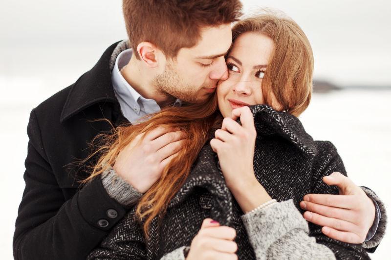 年轻情侣在冬天寒冷的天气里一起感受幸福