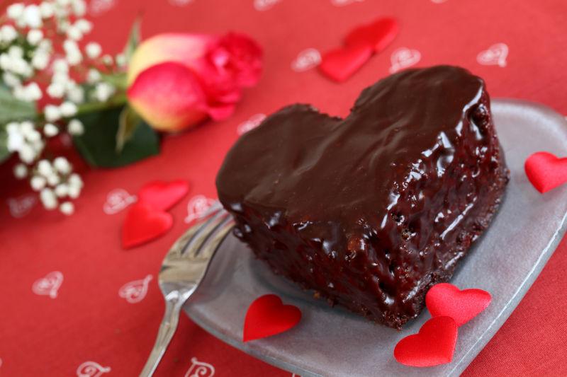 红心背景下的巧克力蛋糕和玫瑰