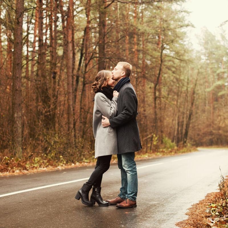 秋天森林公路上亲吻的情侣