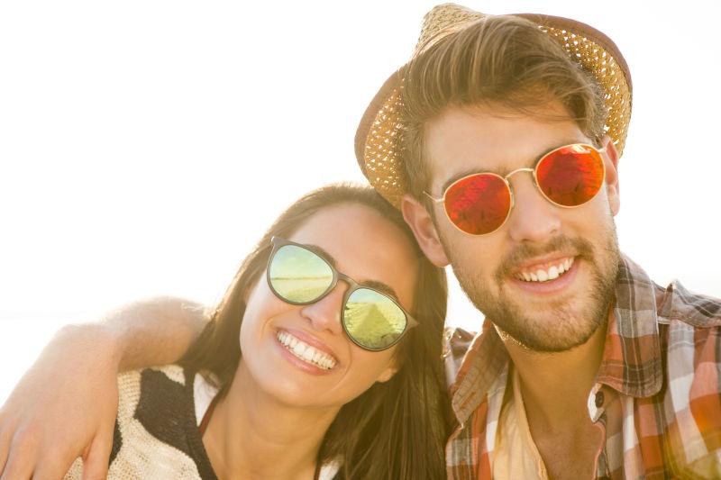 海滩上的年轻夫妇带着墨镜很开心