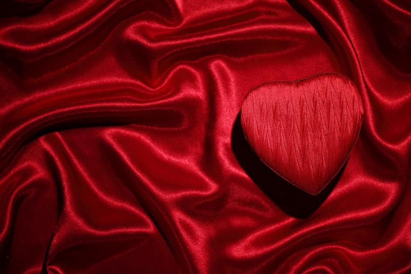 红色丝绸背景中的心形礼物