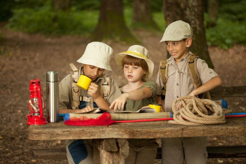 坐在木桌旁讨论地图的野外探险的孩子们