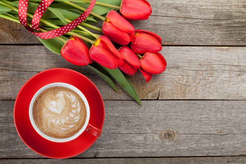 木制背景上的红色郁金香和咖啡