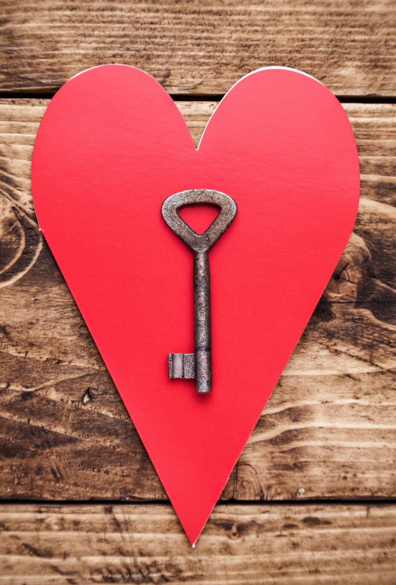 木制背景上红色爱心上的旧钥匙