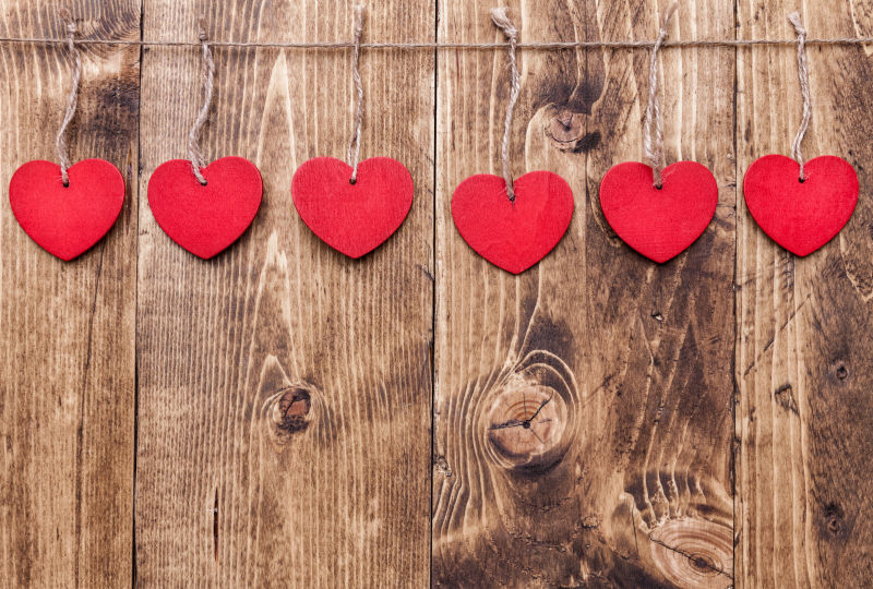 木制背景上挂在绳子上的红色爱心