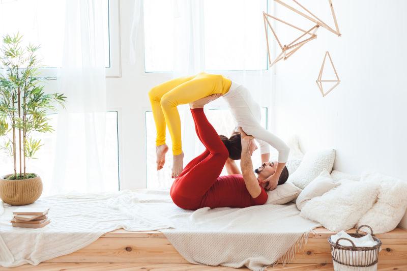 木床上练习瑜伽的夫妇