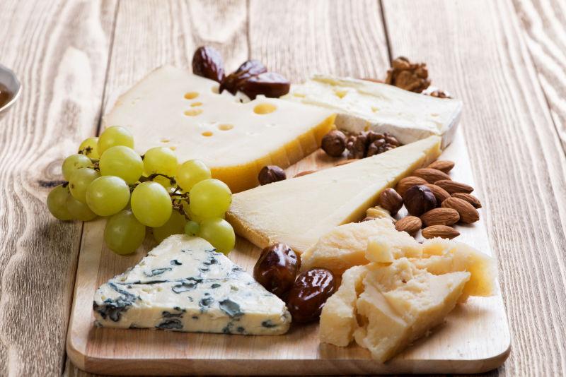 砧板上的葡萄和坚果以及不同的奶酪