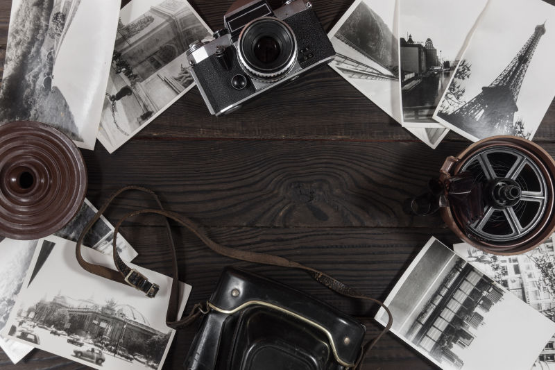 旧木桌上的黑白相片和复古相机