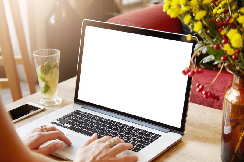 年轻女性职业者的空白屏幕的笔记本电脑和手机
