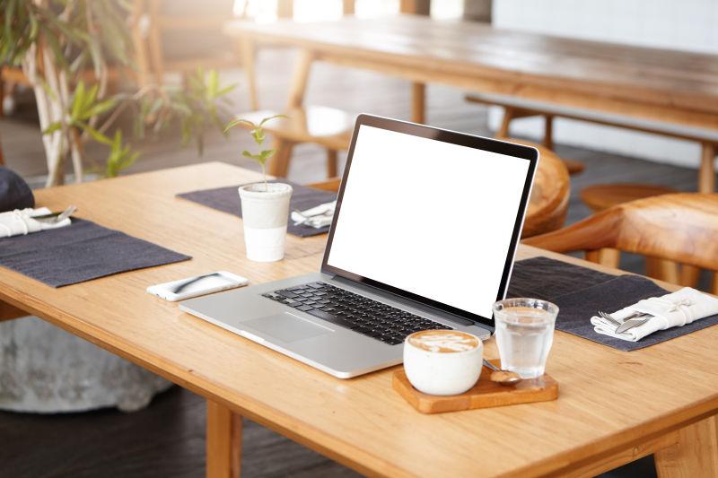餐桌上的笔记本电脑和手机咖啡杯餐具