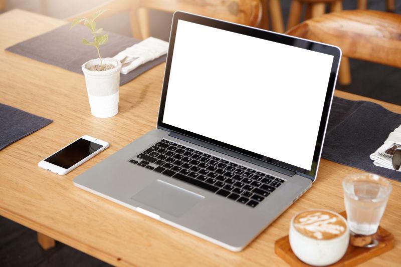 手机咖啡水杯和木桌上的笔记本电脑
