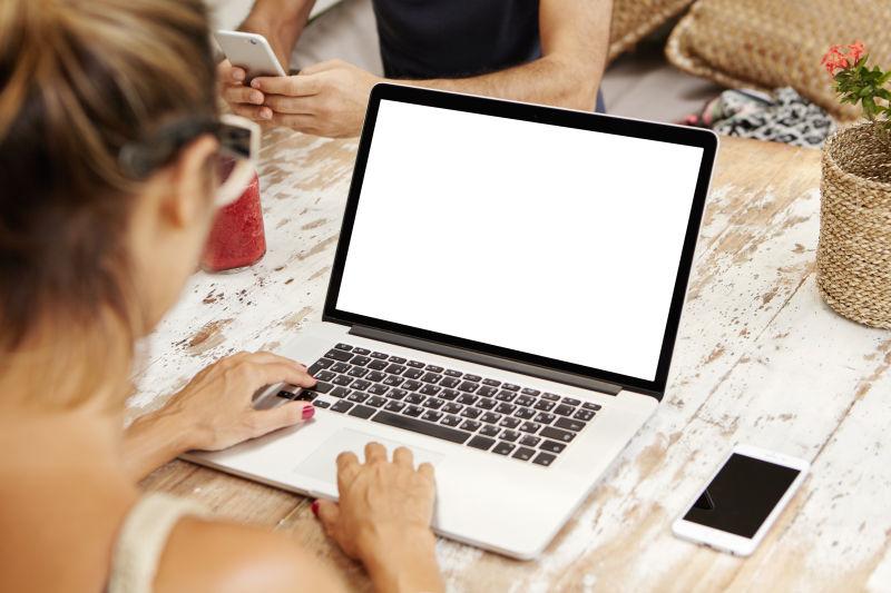 女子在空白屏幕的笔记本电脑上打字