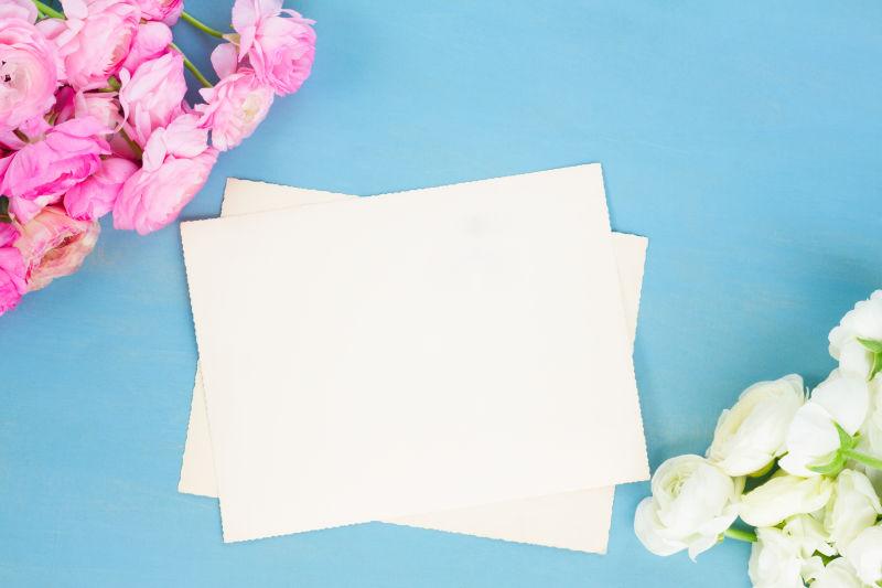 蓝色背景上的空白纸张和毛茛花