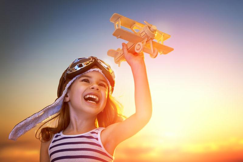 夕阳下开心的玩玩具飞机的女孩