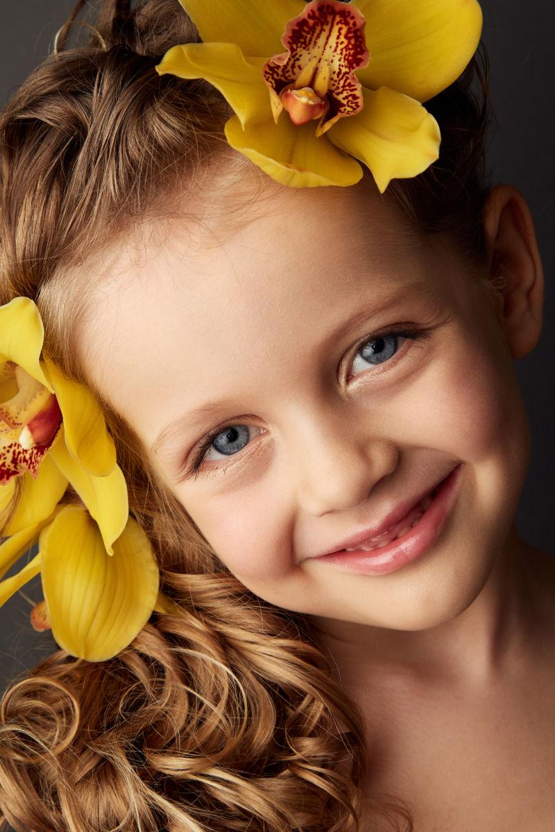 一个美丽的微笑的小女孩她的头发里有兰花