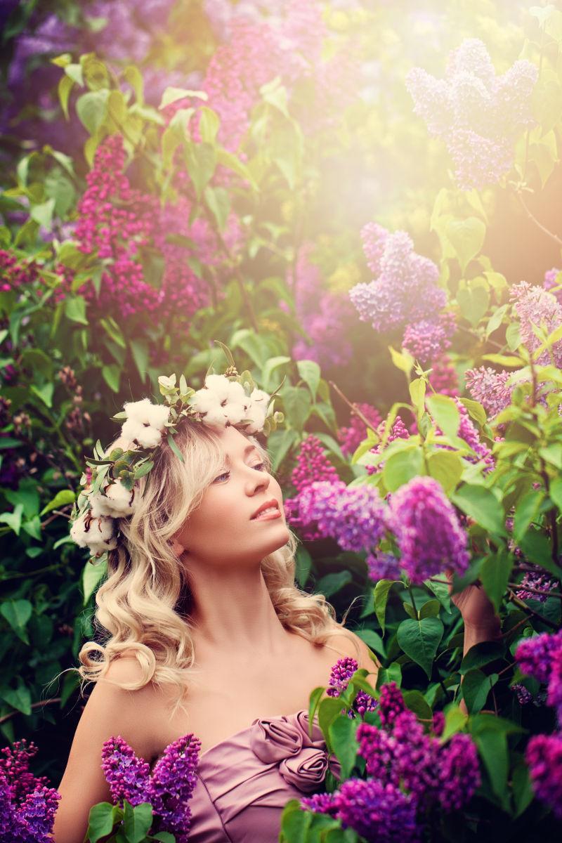 漂亮的金发女人戴着花环在花丛中