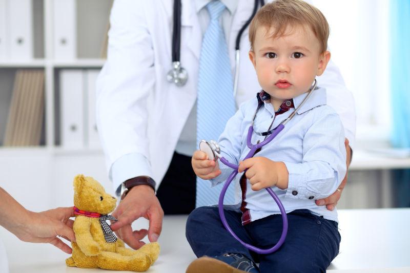 小男孩戴着听诊器检查玩具熊病人