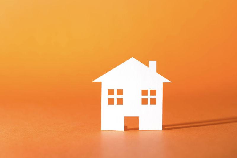 橙色背景上的白色的房屋卡片