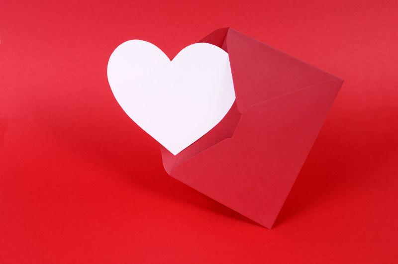 红色背景上的红色信封里的白色心形空白卡片