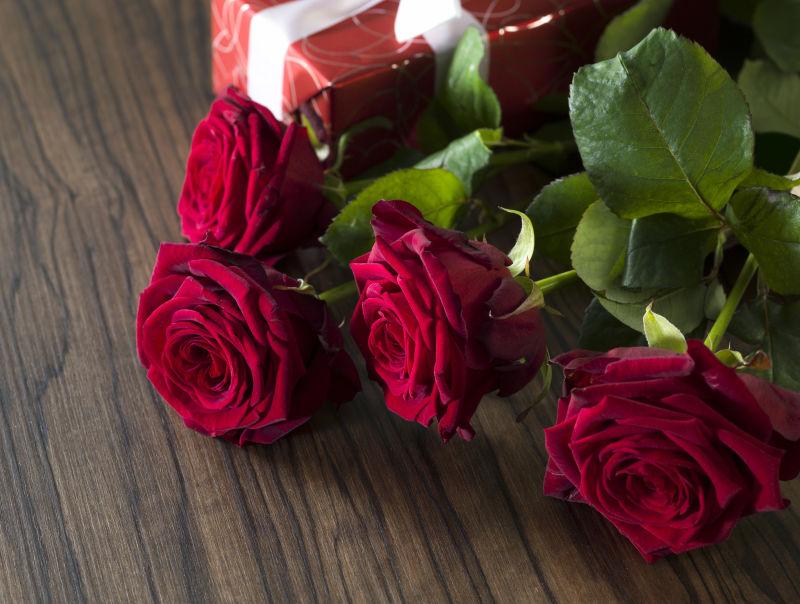 木桌上的红玫瑰与礼盒