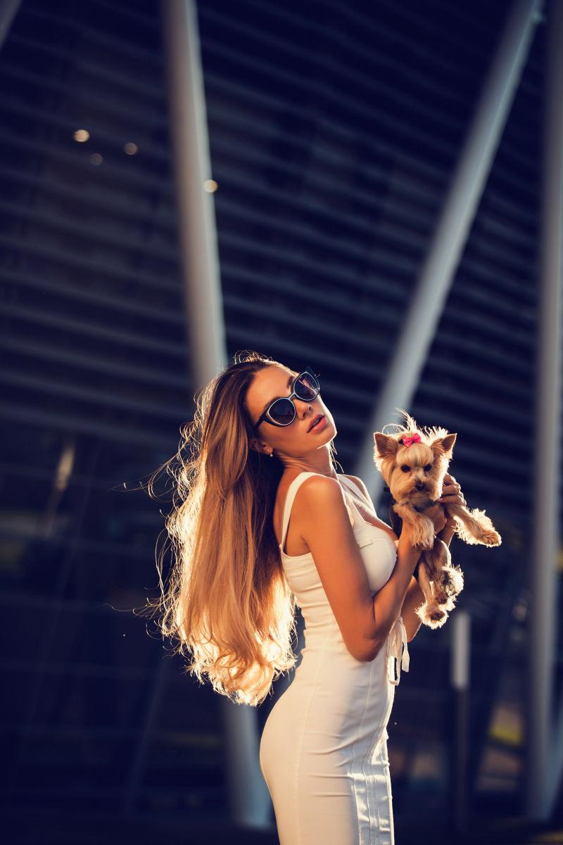 带着太阳眼镜抱着宠物狗的年轻女人