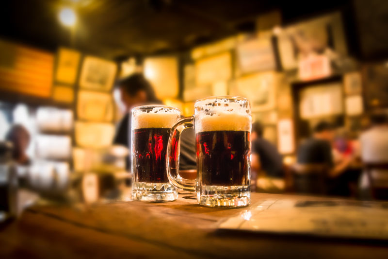 酒吧模糊背景上的两杯啤酒